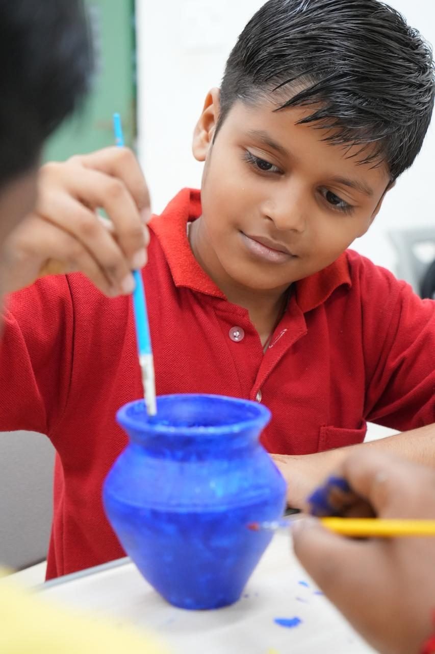 A student painting a clay pot in an art class