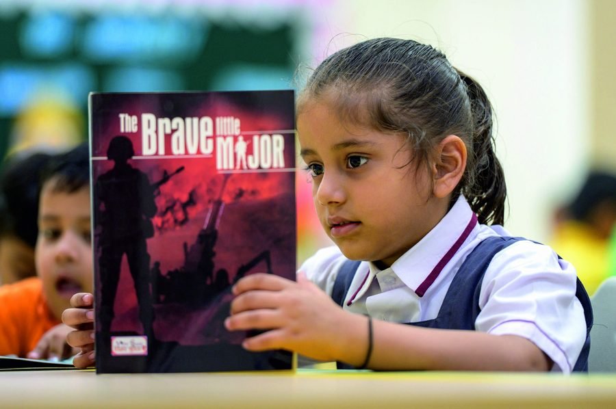 A student reading The Brave Little Major in the library